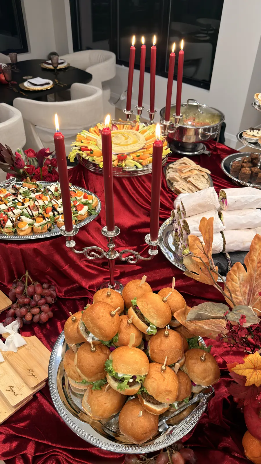 Noosh Catering candlelit grazing table with canapés, mini sandwiches, grapes and sliced fruit.