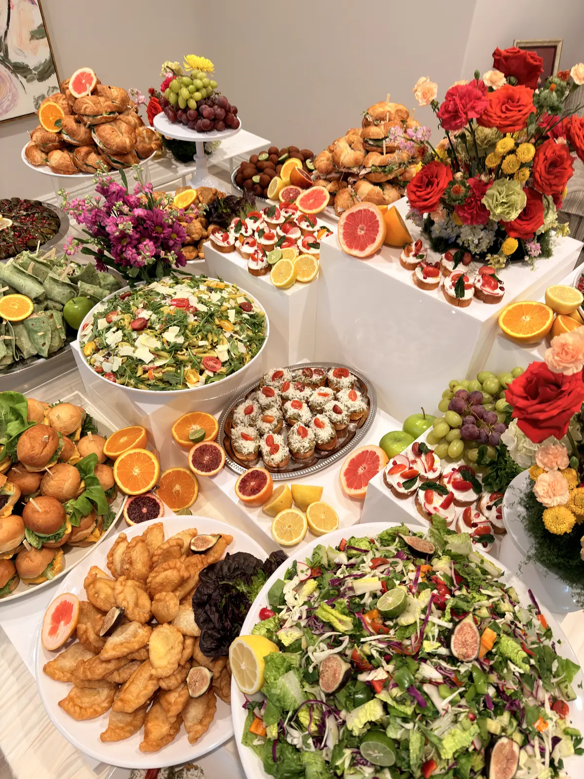 Noosh Catering tiered white grazing display with canapés, salads, roses and fresh citrus.