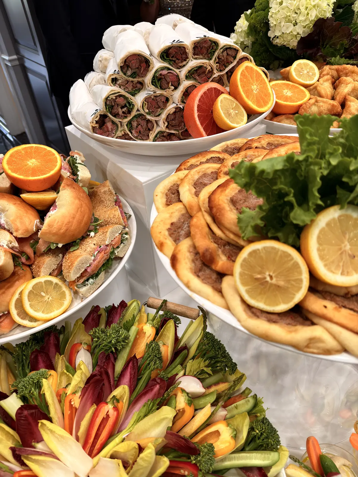 Noosh Catering tiered display with flatbreads, stuffed pastries, bagel sandwiches and crudité.