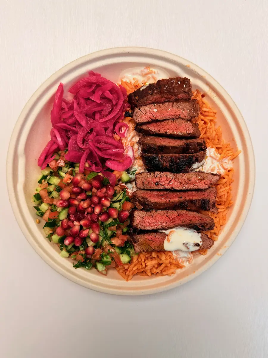 Grilled skirt steak rice bowl with tomato rice and lemon tahini at Fil Fil Mediterranean in Homer Glen, IL.